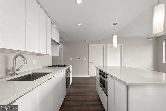 kitchen with appliances with stainless steel finishes, dark wood-type flooring, sink, pendant lighting, and white cabinetry