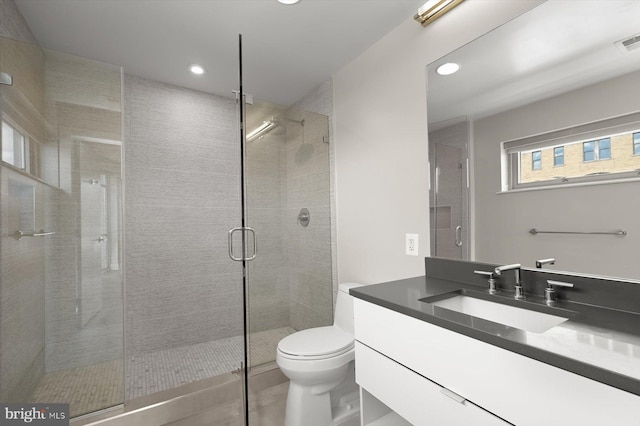 bathroom with tile patterned flooring, a shower with door, vanity, and toilet