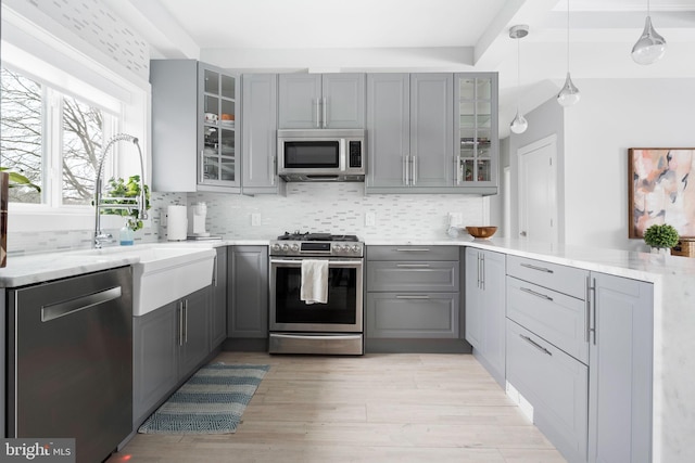 kitchen featuring stainless steel appliances, gray cabinets, and hanging light fixtures