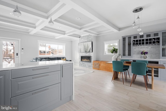 kitchen featuring backsplash, hanging light fixtures, light hardwood / wood-style flooring, gray cabinets, and a fireplace