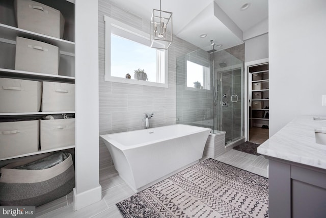 bathroom featuring separate shower and tub, vanity, and tile walls