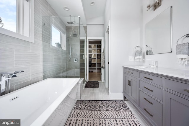 bathroom with tile patterned flooring, vanity, plus walk in shower, and vaulted ceiling