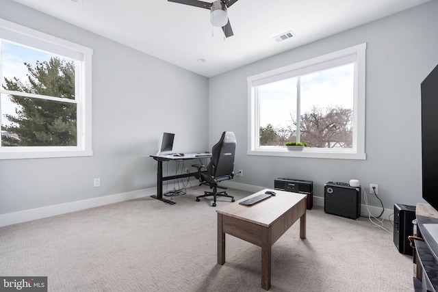 carpeted home office with ceiling fan and a healthy amount of sunlight