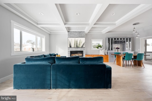 living room featuring beam ceiling, a stone fireplace, a wealth of natural light, and coffered ceiling