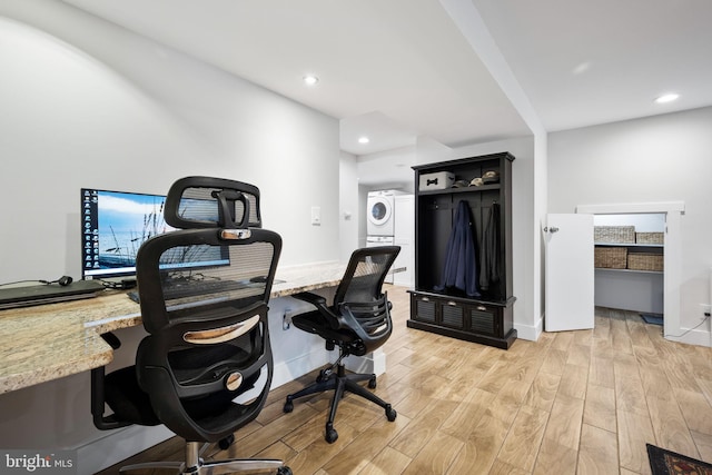 office space with stacked washing maching and dryer and light hardwood / wood-style flooring