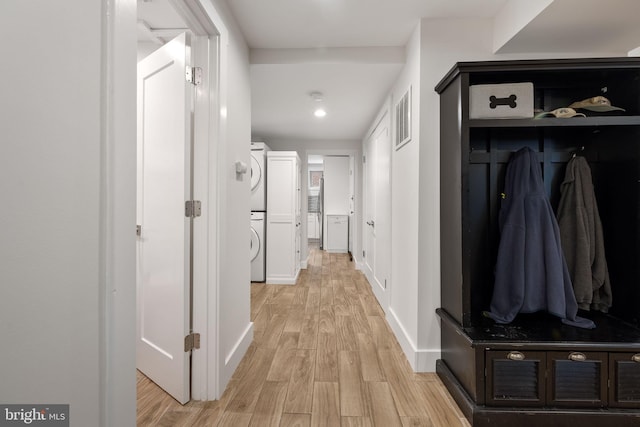 hallway featuring stacked washer and dryer and light hardwood / wood-style floors