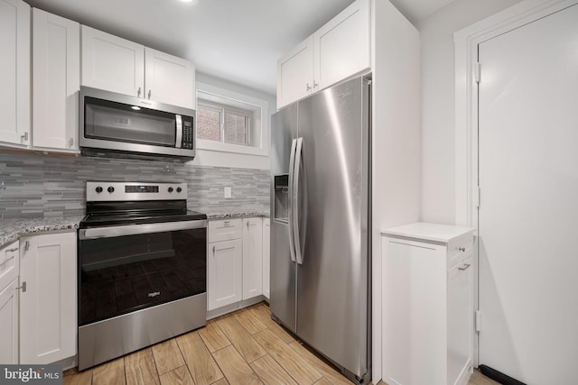 kitchen with backsplash, light stone countertops, white cabinets, and appliances with stainless steel finishes