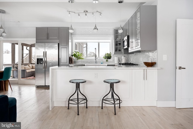 kitchen featuring a breakfast bar area, kitchen peninsula, gray cabinetry, and stainless steel appliances