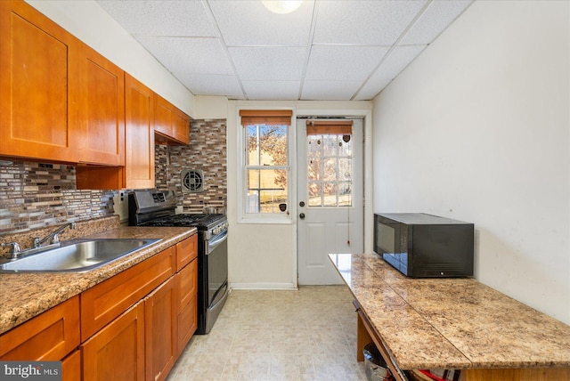 kitchen featuring backsplash, stainless steel range with gas cooktop, a paneled ceiling, and sink