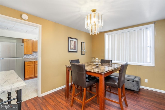 dining area featuring dark hardwood / wood-style flooring and an inviting chandelier