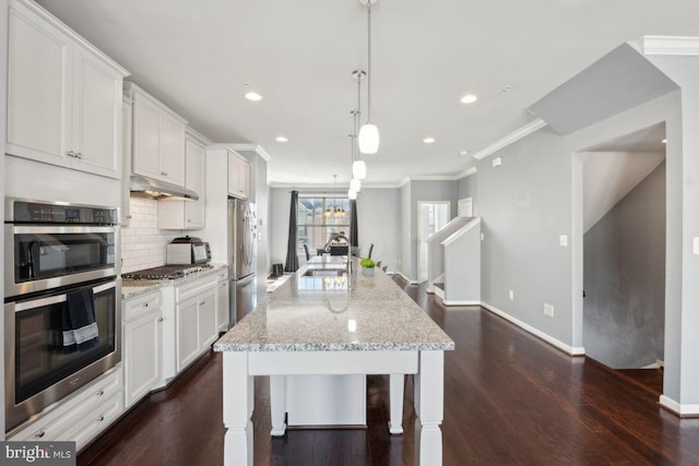 kitchen with hanging light fixtures, a center island with sink, white cabinets, and stainless steel appliances