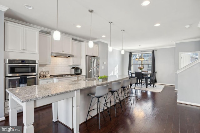 kitchen featuring pendant lighting, white cabinetry, and a large island with sink