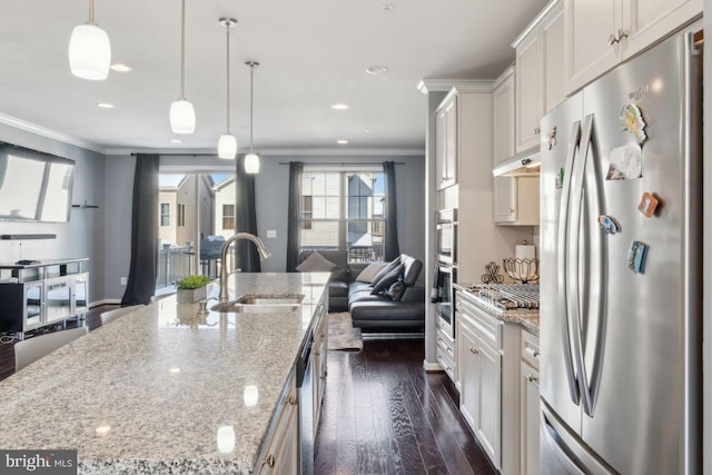 kitchen featuring a large island with sink, white cabinets, sink, light stone countertops, and stainless steel appliances