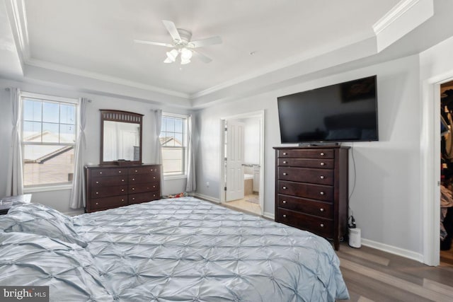 bedroom featuring a tray ceiling, connected bathroom, ceiling fan, and multiple windows