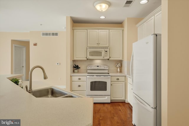 kitchen featuring white appliances, tasteful backsplash, sink, and hardwood / wood-style flooring