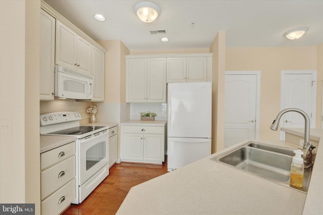 kitchen featuring sink, white cabinetry, white appliances, hardwood / wood-style floors, and backsplash