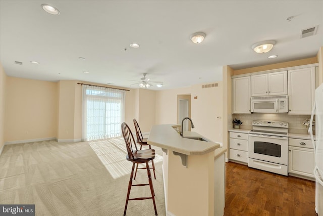 kitchen featuring white appliances, a kitchen bar, white cabinetry, and sink