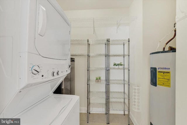 laundry area with stacked washer / drying machine, light tile patterned floors, and water heater