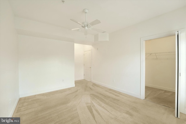 unfurnished bedroom featuring ceiling fan, light colored carpet, a spacious closet, and a closet