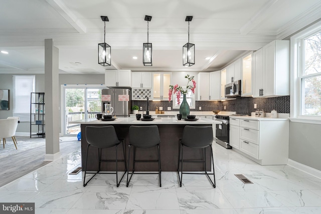 kitchen with appliances with stainless steel finishes, ornamental molding, pendant lighting, a center island, and white cabinetry