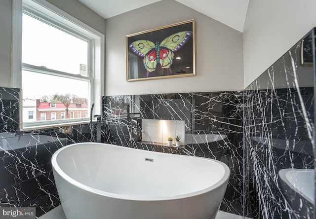 bathroom featuring a tub to relax in and tile walls