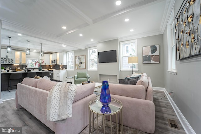 living room with crown molding, sink, beamed ceiling, and dark wood-type flooring