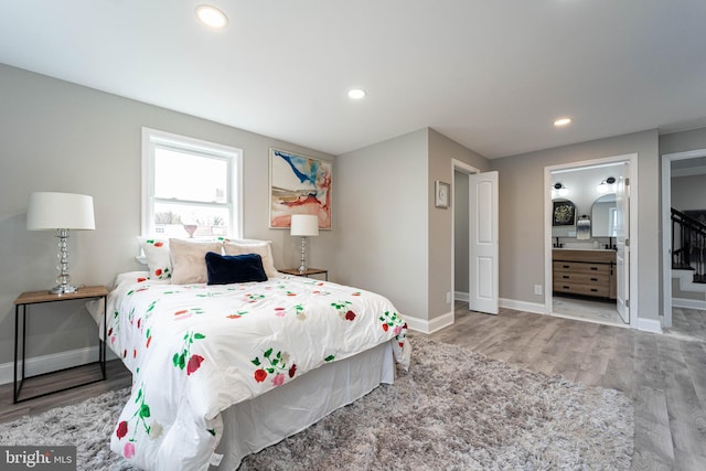 bedroom with ensuite bathroom and light wood-type flooring