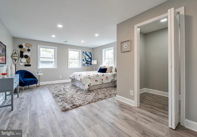 bedroom with multiple windows and light hardwood / wood-style flooring