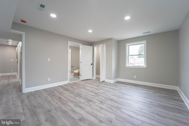 unfurnished bedroom with light hardwood / wood-style floors and connected bathroom