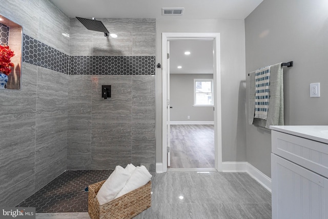 bathroom with a tile shower and vanity