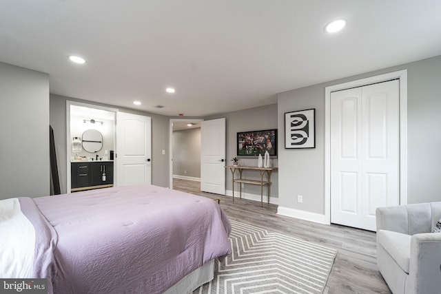 bedroom featuring a closet, light wood-type flooring, and ensuite bath