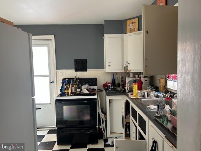 kitchen with black / electric stove, white cabinets, sink, and white fridge