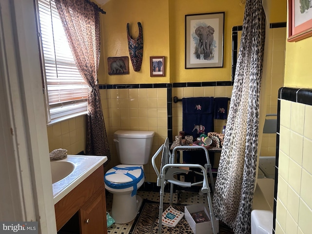 full bathroom featuring tile patterned floors, bathing tub / shower combination, toilet, vanity, and tile walls