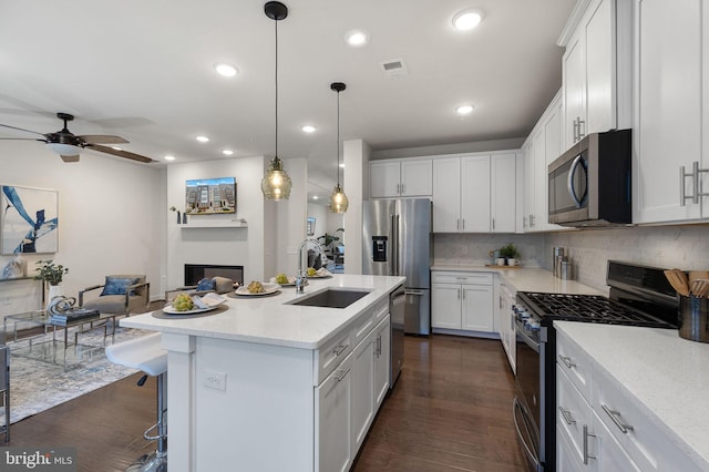 kitchen featuring pendant lighting, white cabinetry, sink, a kitchen island with sink, and stainless steel appliances