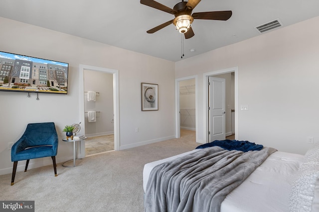 carpeted bedroom featuring ceiling fan, connected bathroom, a closet, and a walk in closet