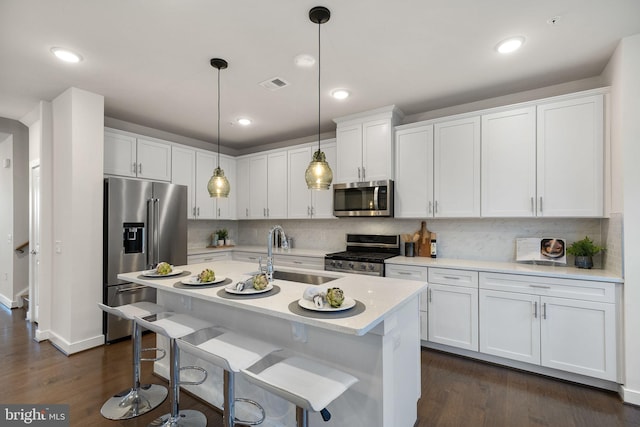 kitchen featuring pendant lighting, stainless steel appliances, sink, and white cabinets