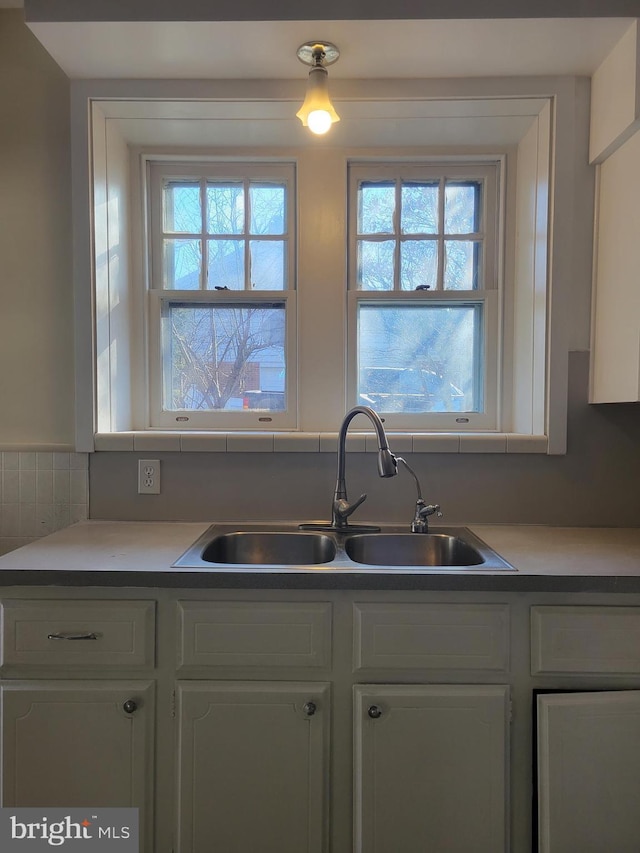 kitchen with white cabinets, sink, and a wealth of natural light