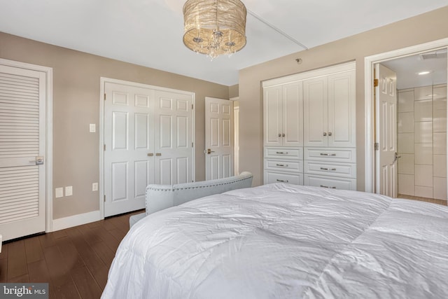 bedroom featuring ensuite bath, dark wood-type flooring, and multiple closets