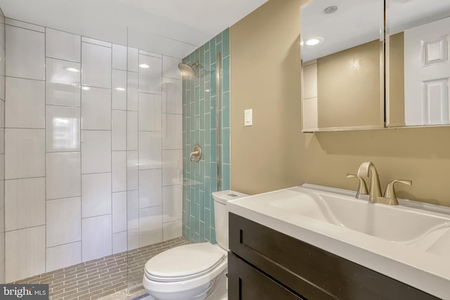 bathroom with vanity, a tile shower, and toilet