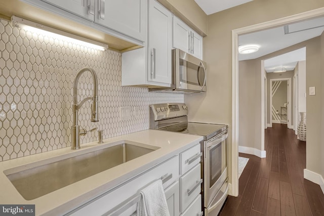 kitchen with sink, dark wood-type flooring, stainless steel appliances, tasteful backsplash, and white cabinets