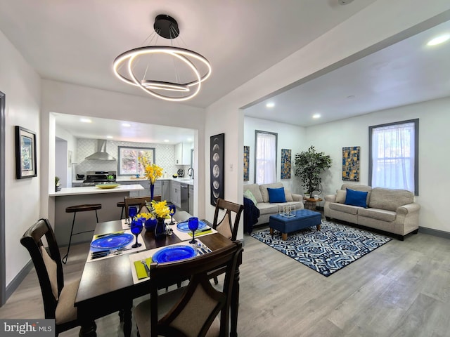 dining area with a chandelier, light wood-type flooring, and sink