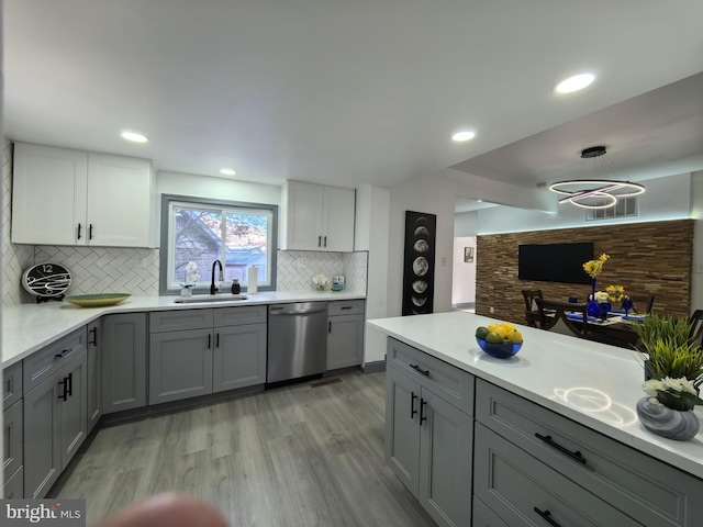 kitchen featuring backsplash, dishwasher, gray cabinetry, and sink