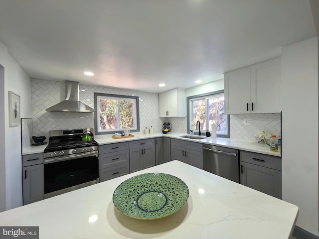 kitchen featuring backsplash, sink, stainless steel appliances, and wall chimney range hood