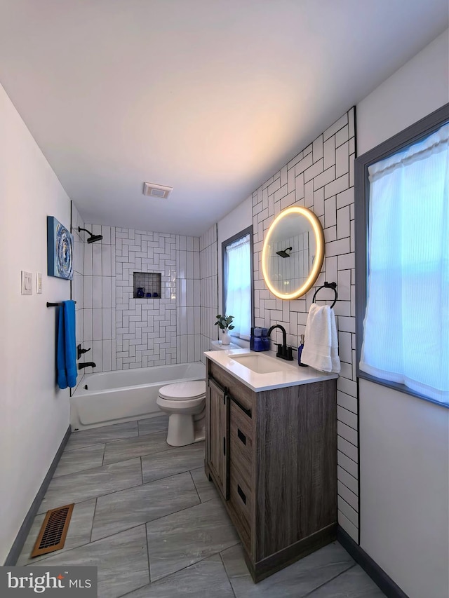 full bathroom with vanity, tiled shower / bath combo, and toilet