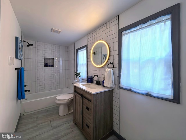 full bathroom with vanity, tiled shower / bath combo, and toilet