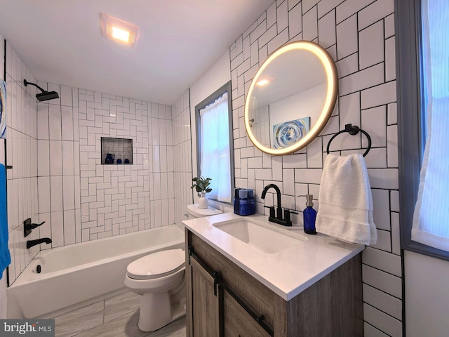 full bathroom with vanity, tiled shower / bath combo, toilet, and tile walls