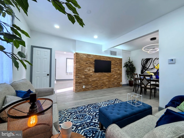 living room featuring a fireplace, beam ceiling, and light wood-type flooring