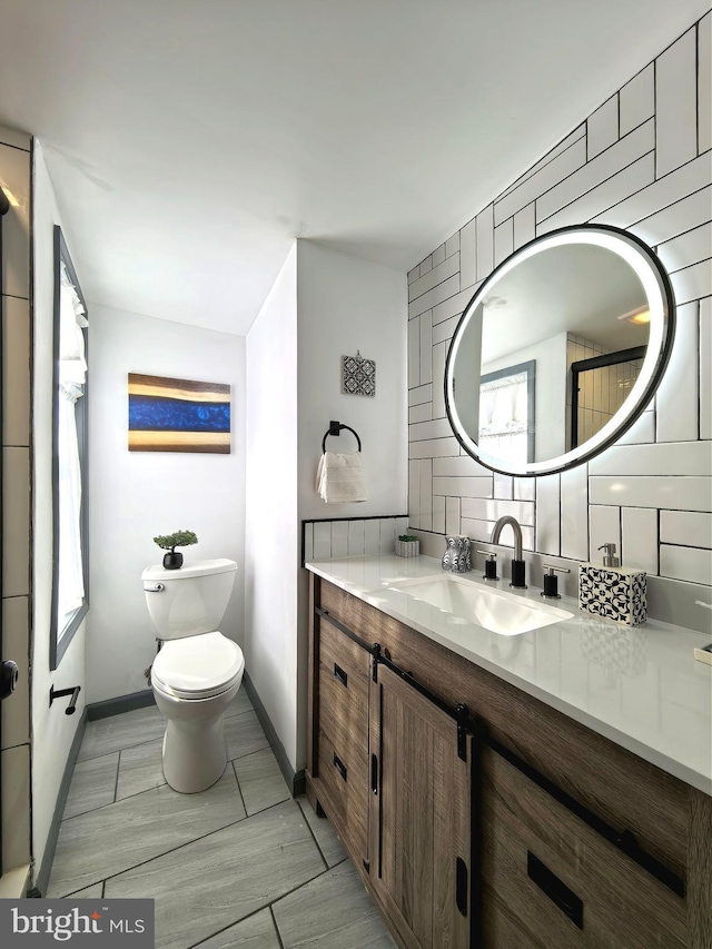 bathroom with vanity, toilet, and tasteful backsplash