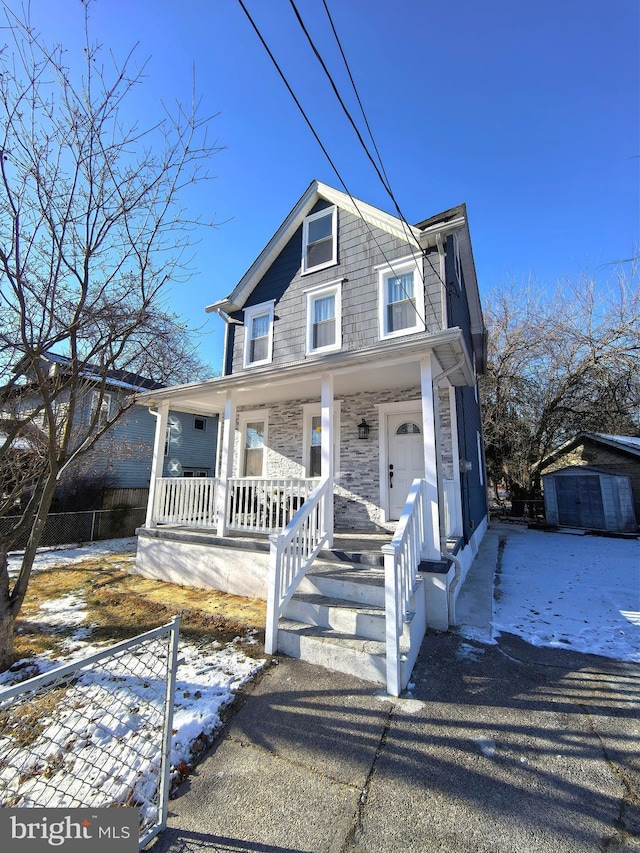 view of front of property featuring a porch and a storage shed