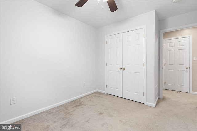 unfurnished bedroom with ceiling fan, light colored carpet, and a closet